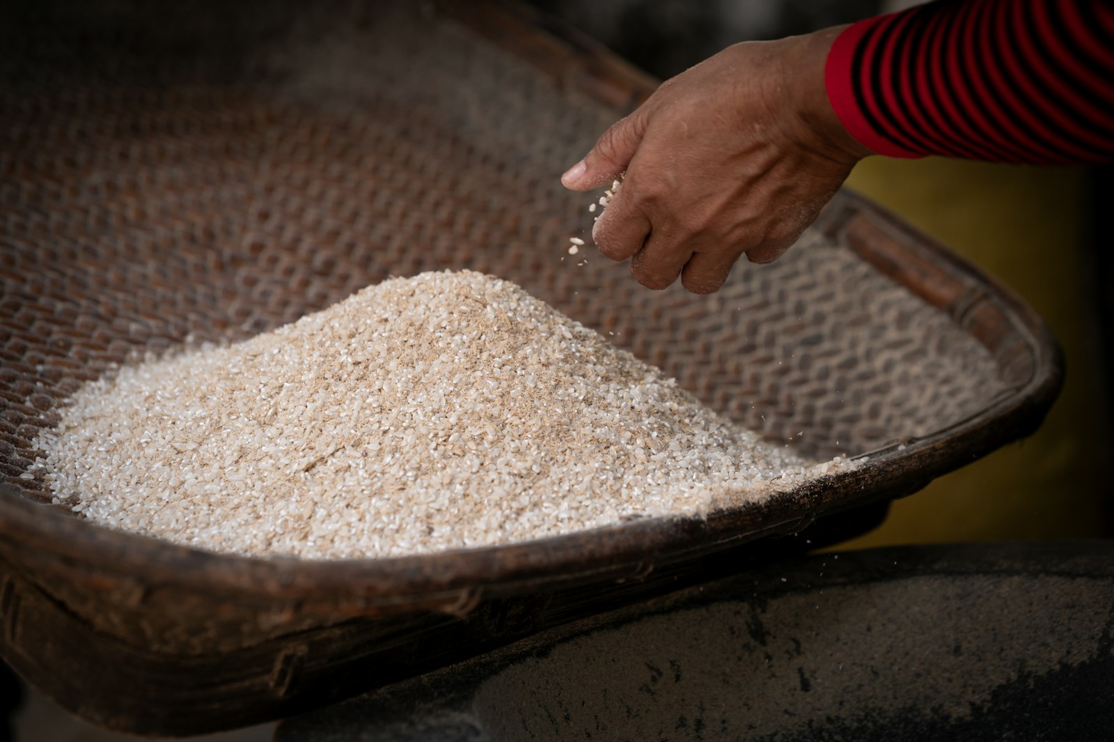 A person scooping rice out of a basket